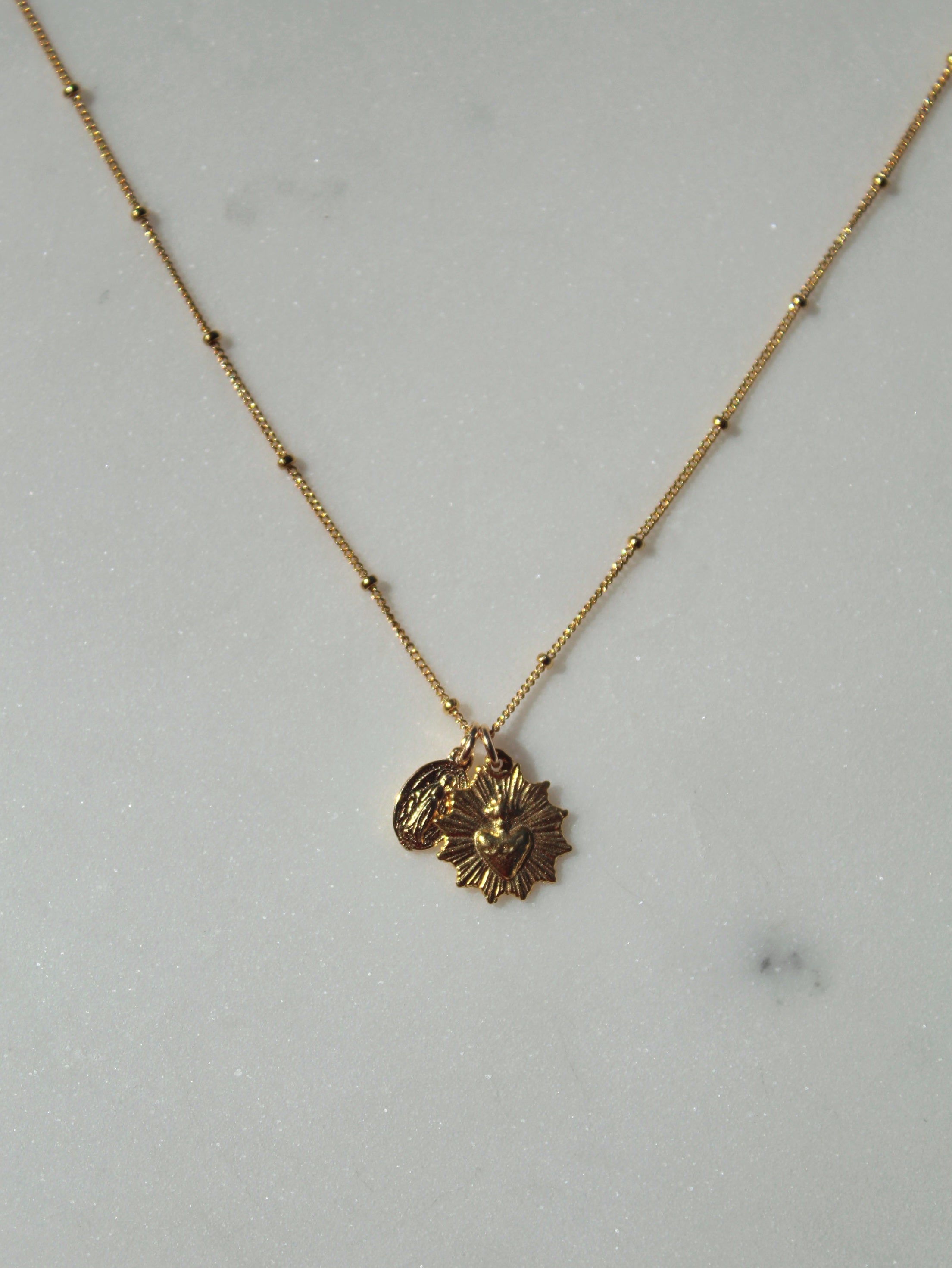 Gold-tone pendant necklace with heart and starburst charms on short chain