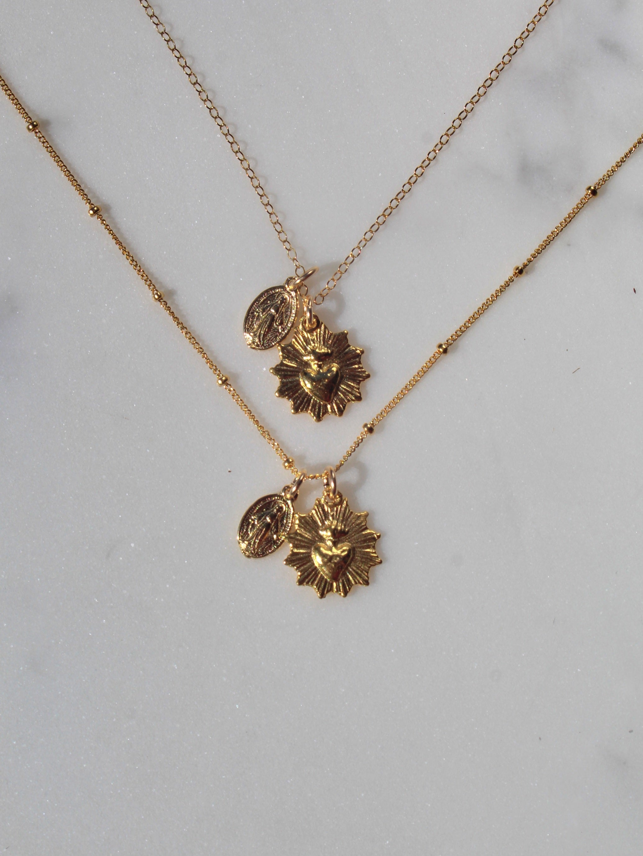 Gold-tone necklace featuring two round religious medallion pendants on chain