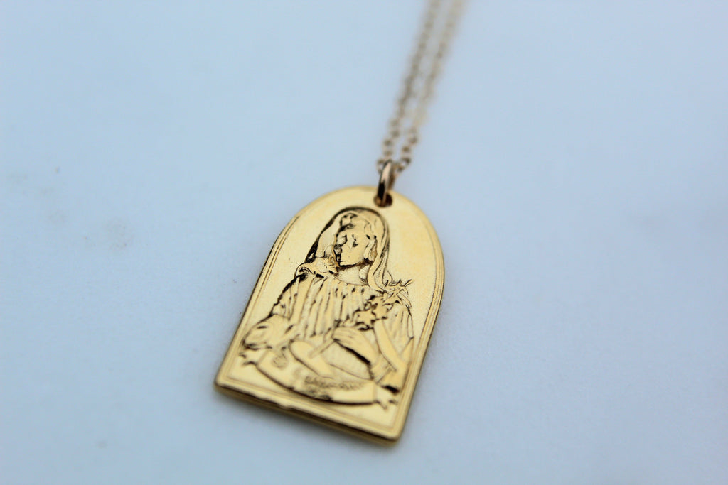 Gold-tone St. Catherine pendant necklace with raised arch portrait charm on chain.