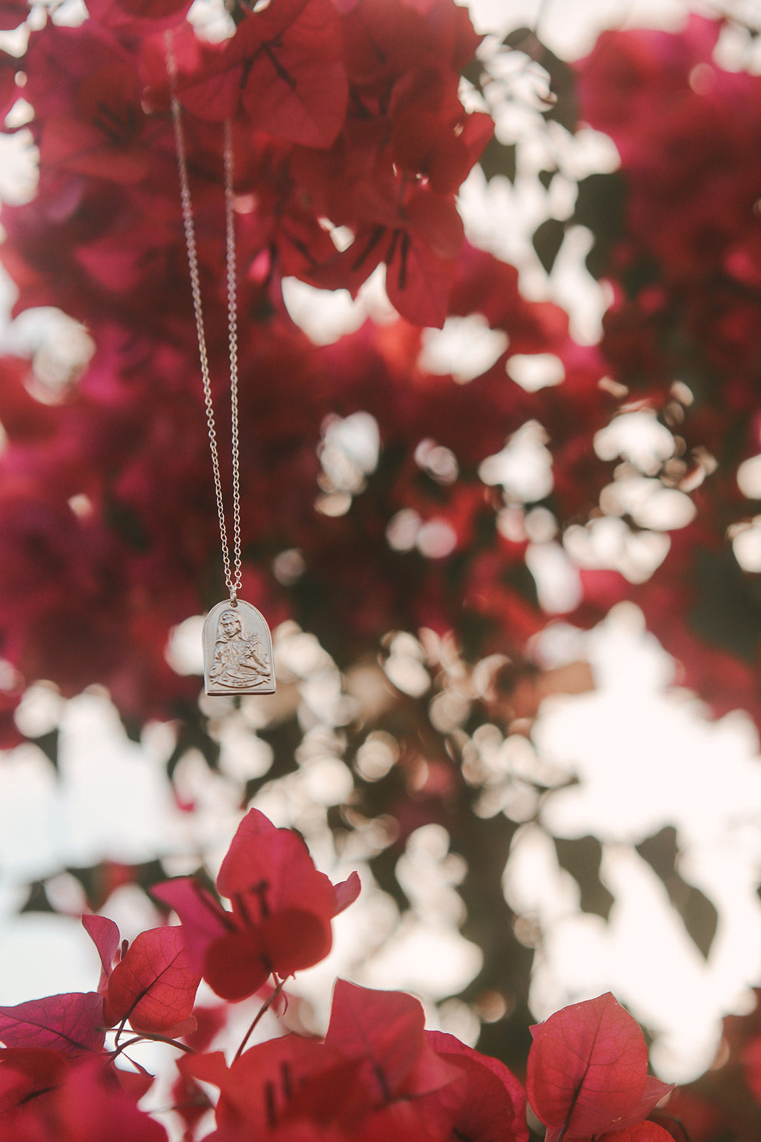 Sterling silver necklace with small heart saint pendant hanging from a chain