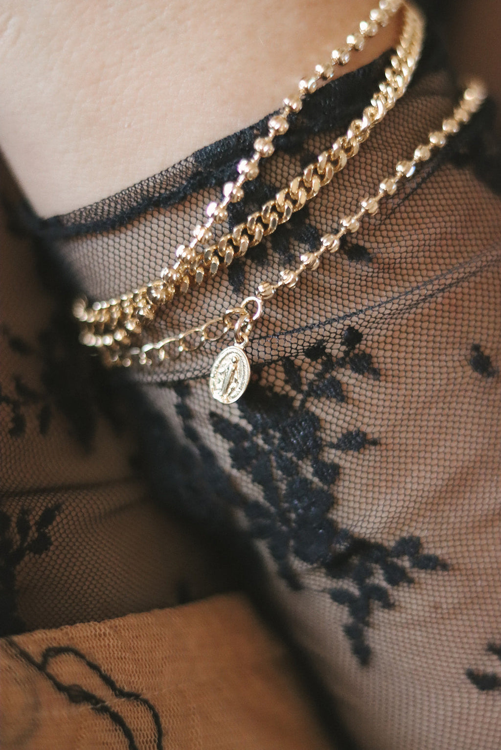 Layered gold-tone bracelets with oval medal charm and chain details