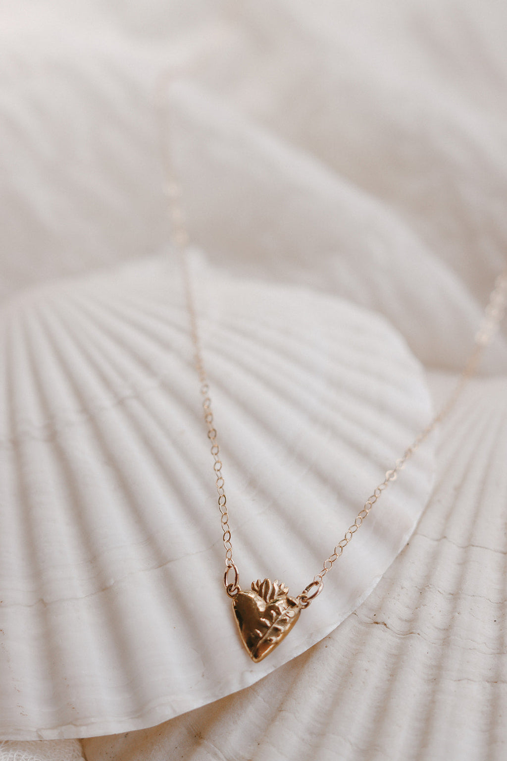 Gold-tone heart pendant necklace with thin chain on white fabric