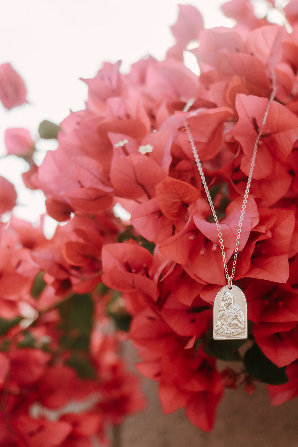 Sterling silver Saint pendant necklace with oval frame and tiny seated figure