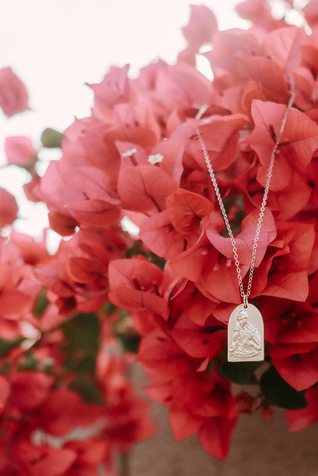 Sterling silver Saint pendant necklace with oval frame and tiny seated figure