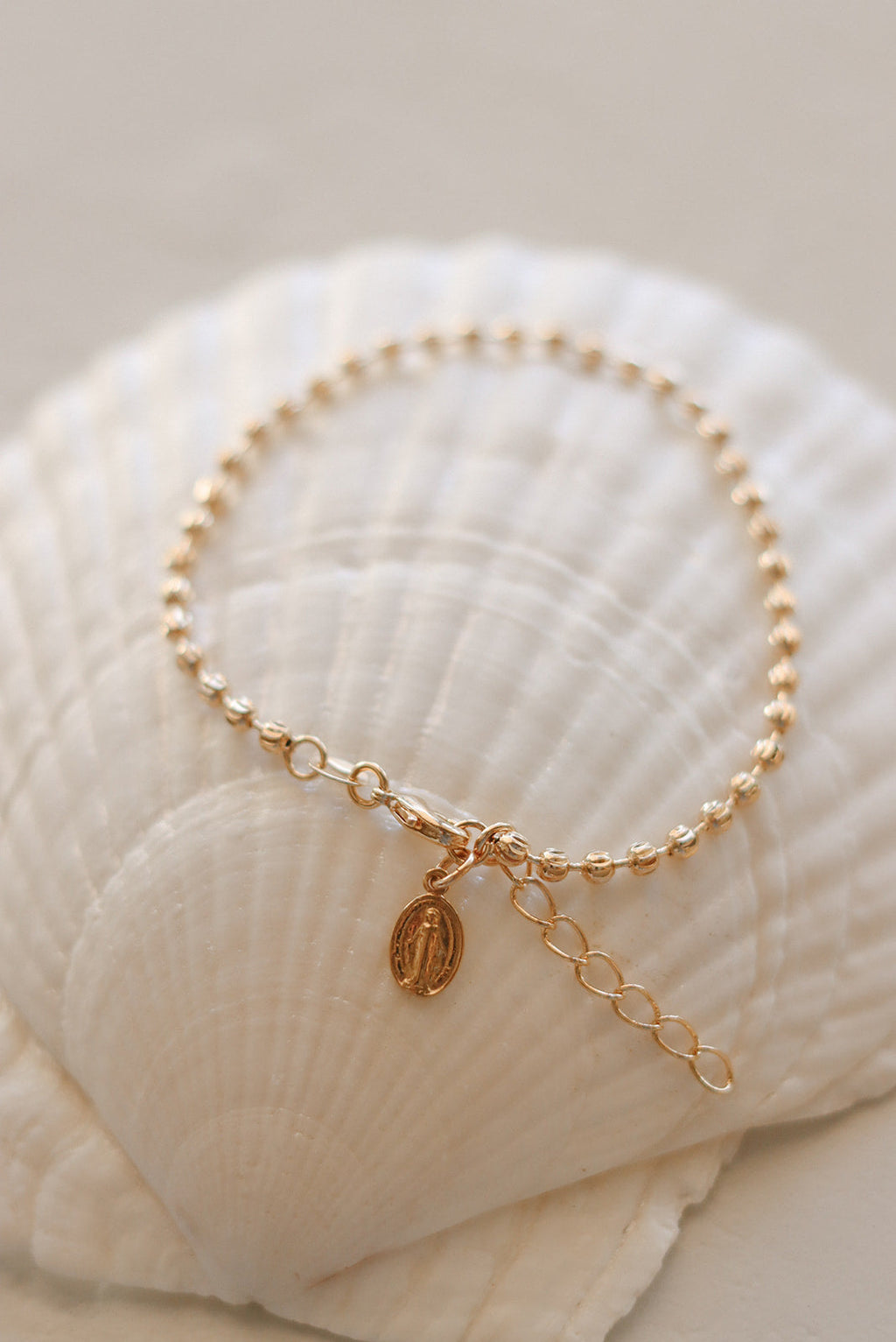 Gold-tone medal charm bracelet with beaded chain and oval dangling pendant