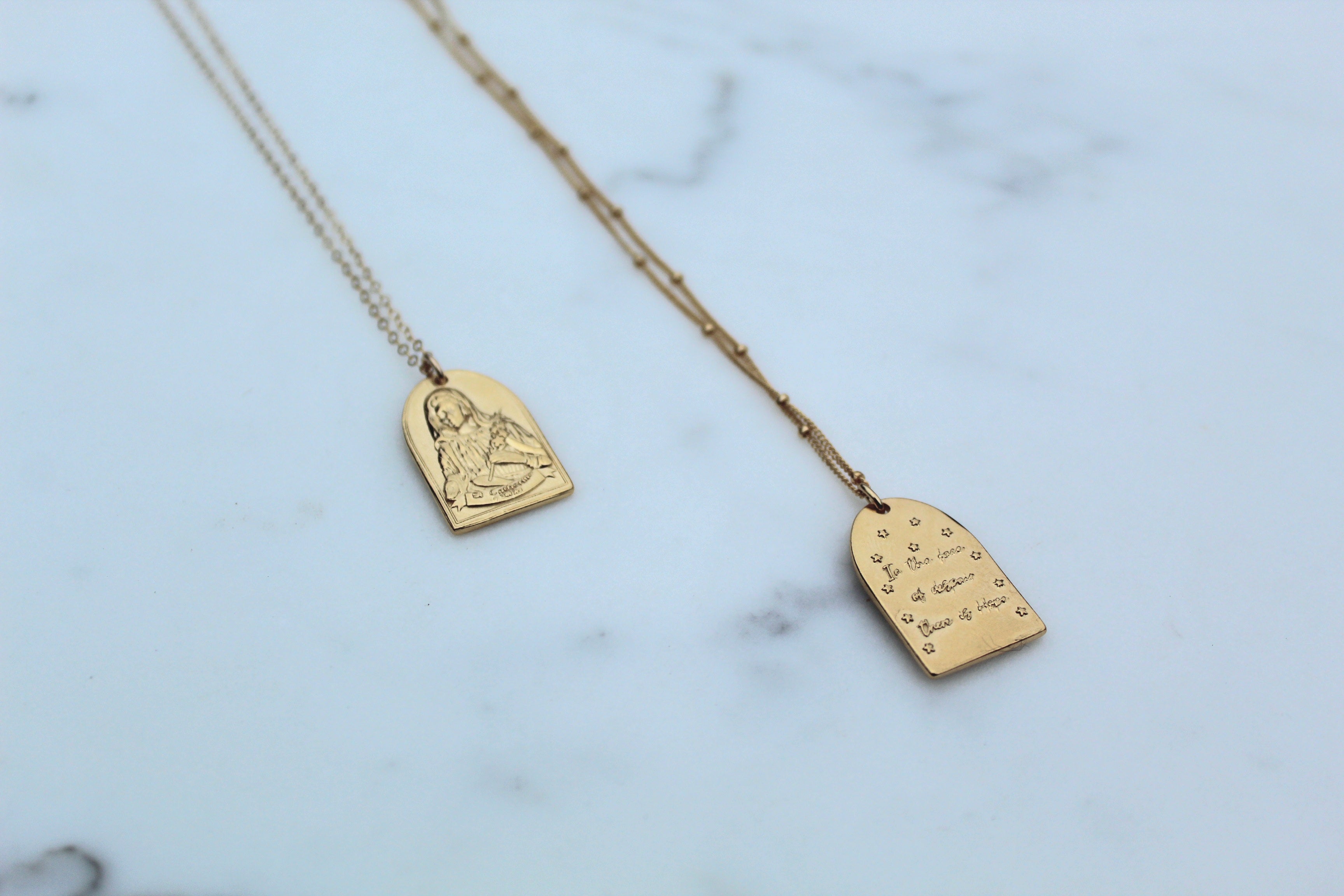 Gold-tone St. Catherine pendant necklace with portrait and script arch charms.