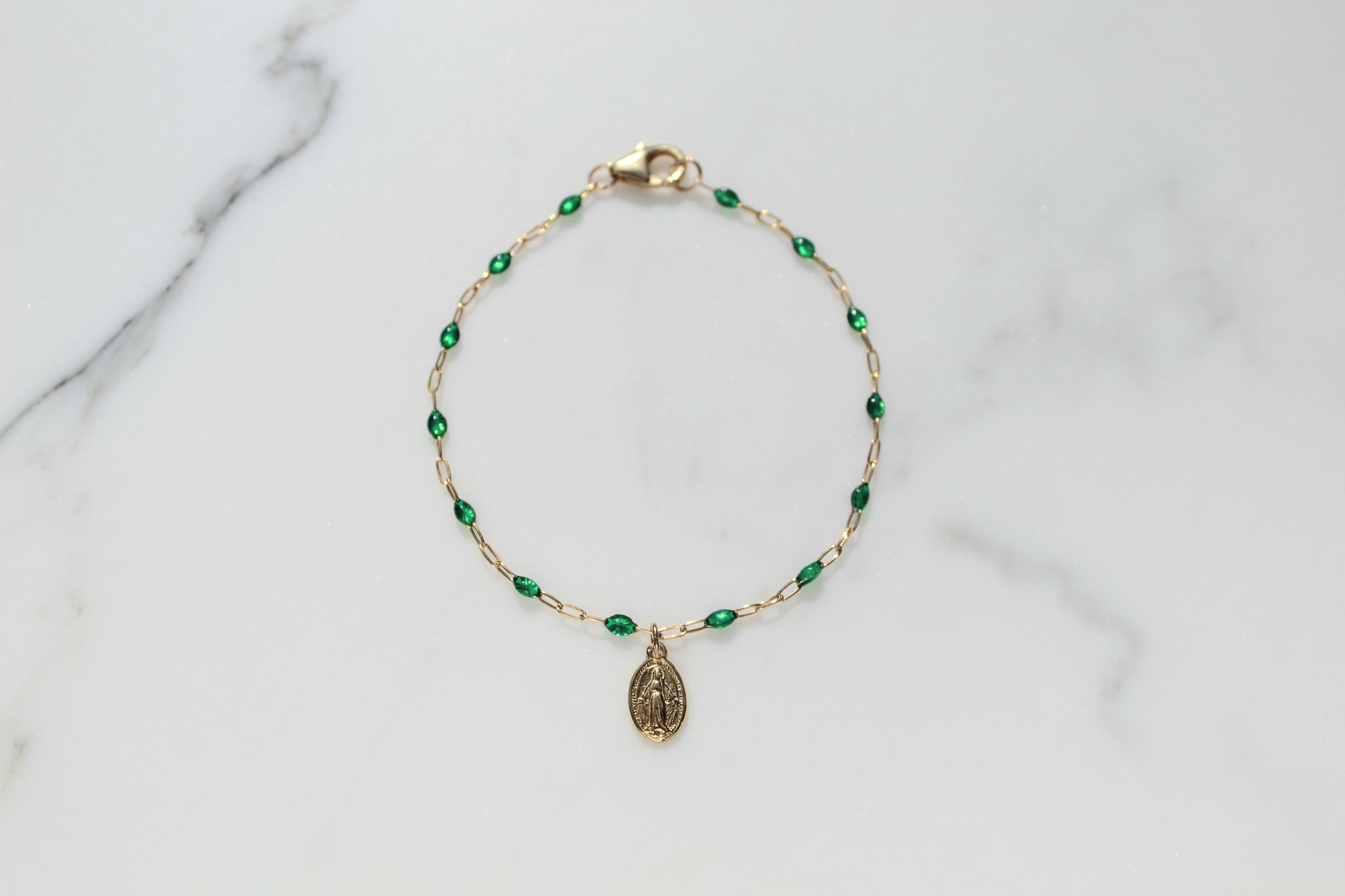 Gold-tone beaded bracelet with green teardrop beads and oval medal charm