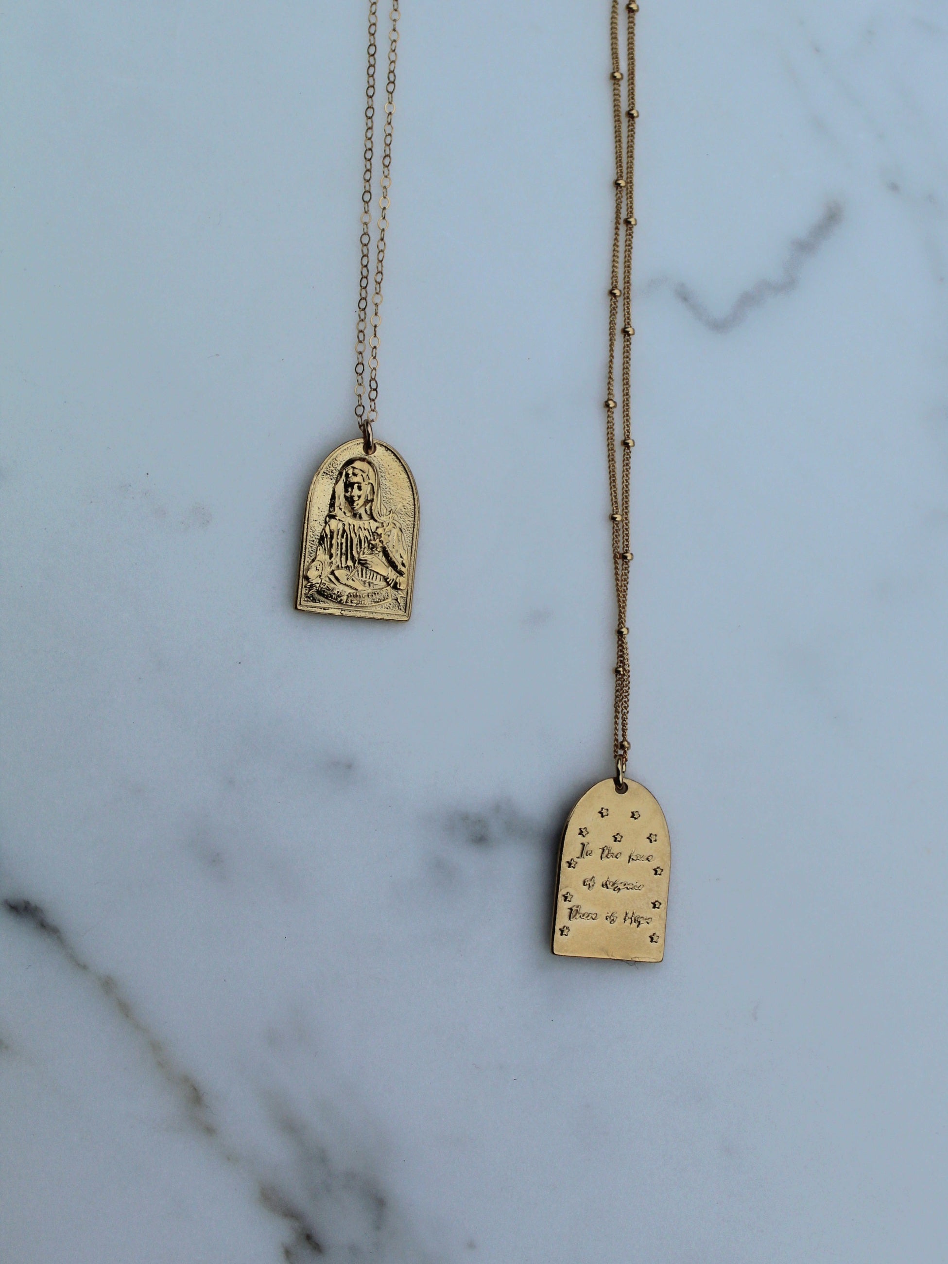 Gold-tone St. Catherine pendant necklace with two arch charms and extended chain links.