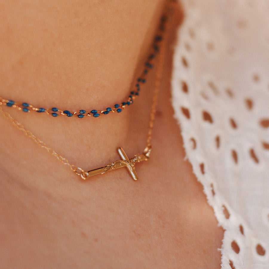 Gold-tone cross pendant necklace with blue beaded chain detail