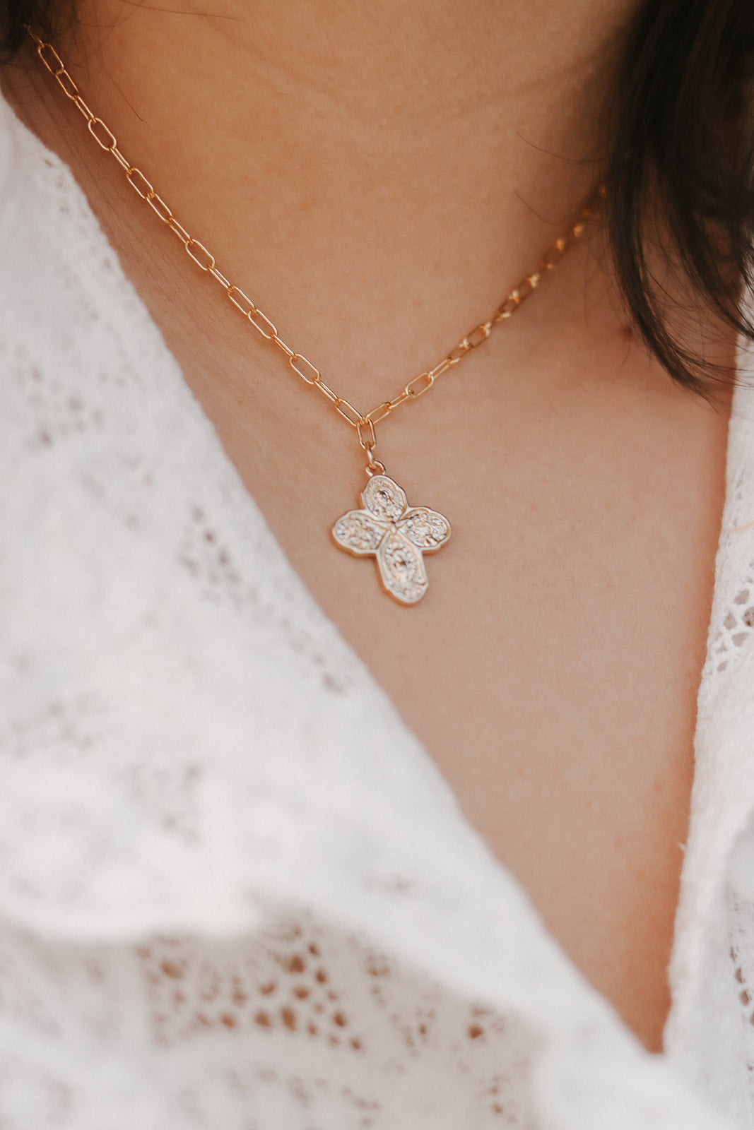 Gold paperclip chain necklace with textured cross pendant on neckline