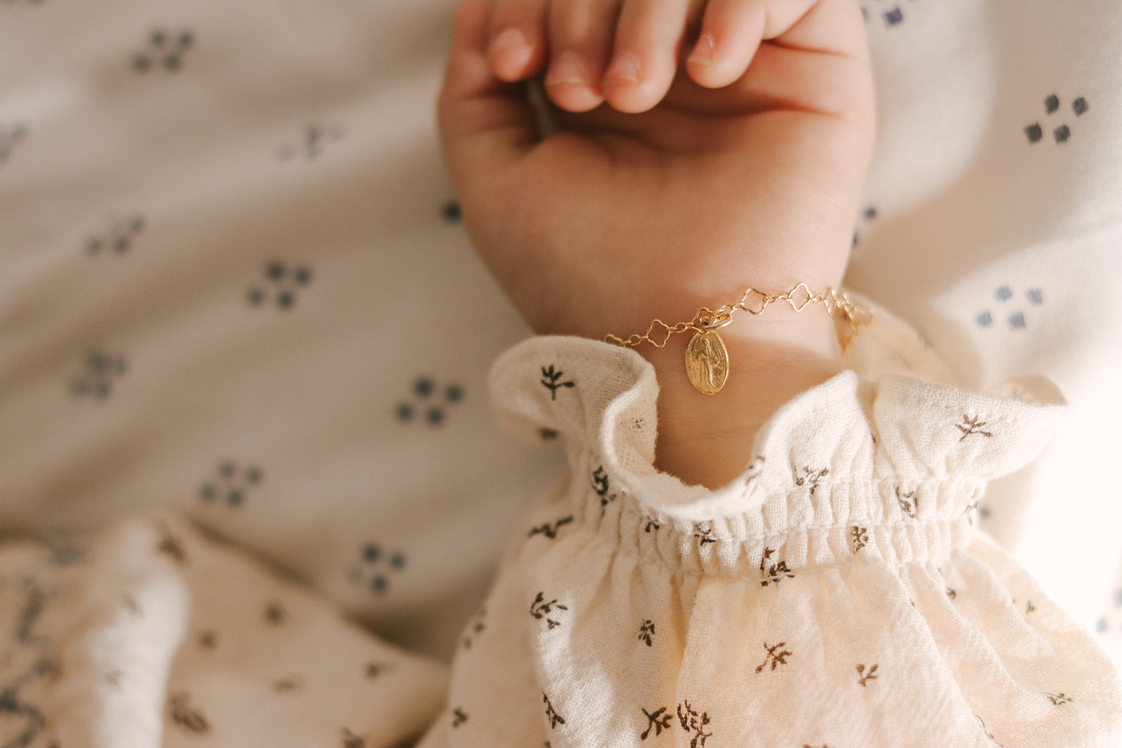 Gold-tone charm bracelet with oval medal charm on child's wrist