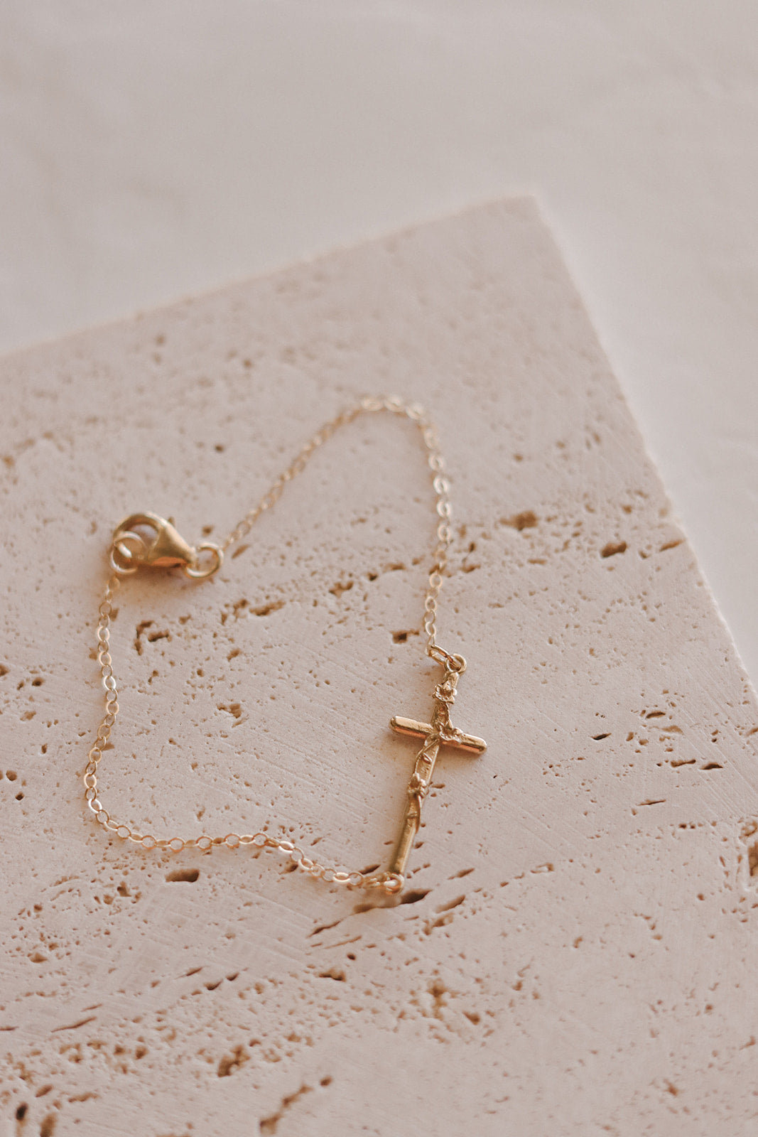 Gold-tone cross charm bracelet with linked chain and small centerpiece charm