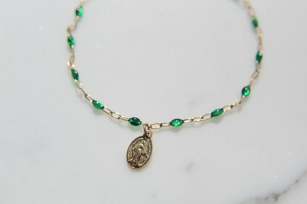 Green beaded bracelet with oval medal pendant on gold chain links