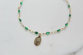 Green beaded bracelet with oval medal pendant on gold chain links