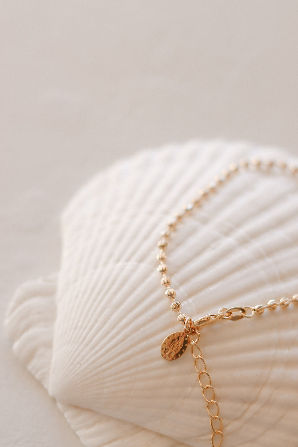 Gold-tone bracelet with oval medal charm and small dangling charm