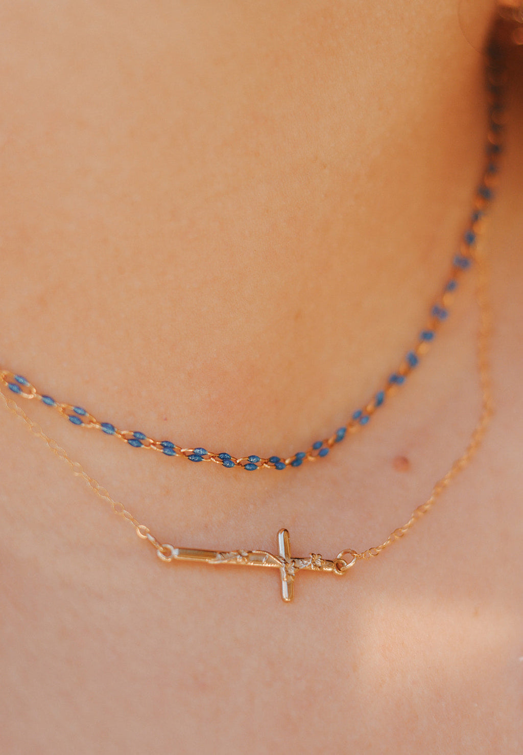 Necklace with gold-tone cross charm and a blue beaded layer chain.