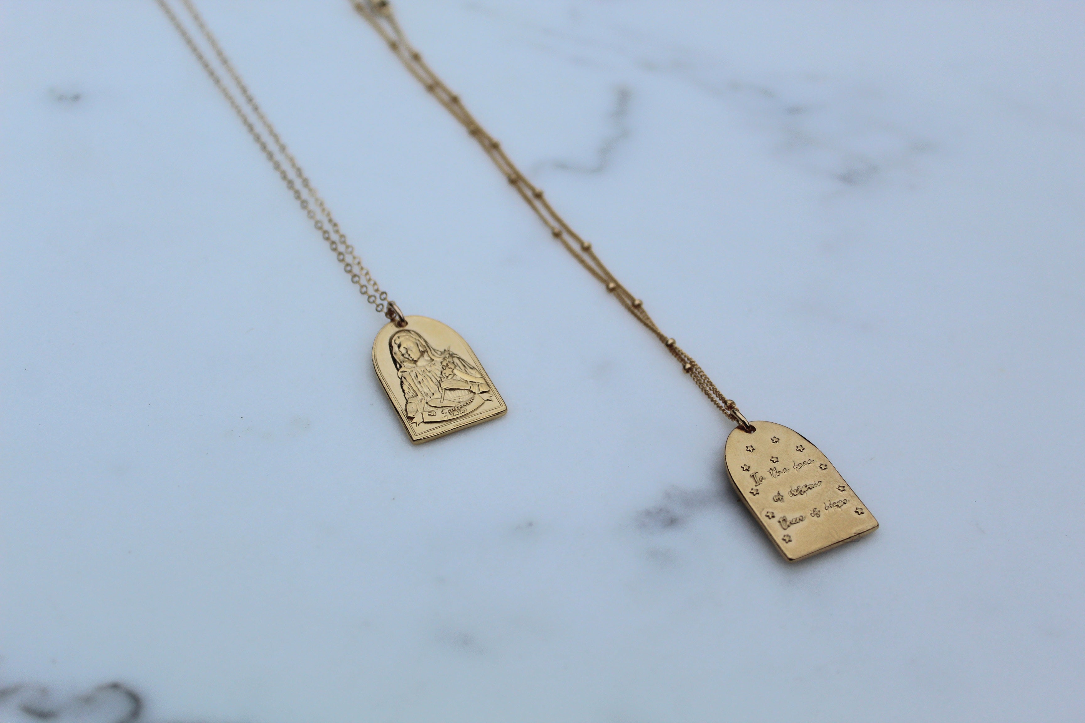 Gold-tone St. Catherine pendant necklace set with two arch charms on chains.