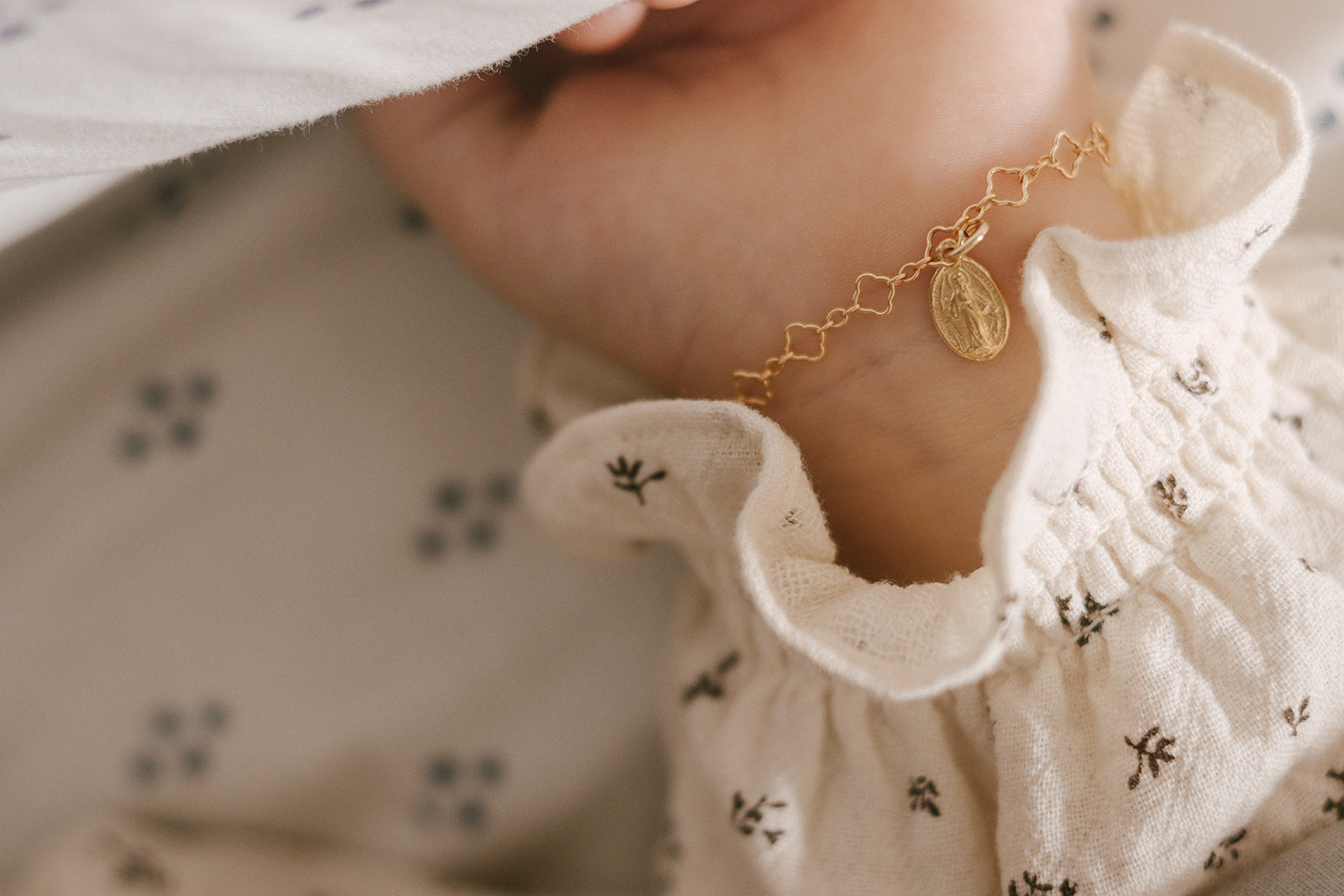 Gold children’s charm bracelet with oval medal pendant on a child’s wrist.