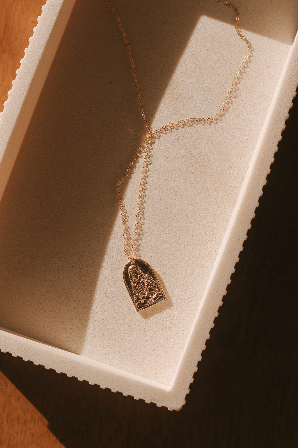Gold-tone St. Catherine pendant necklace with arch charm displayed on chain.