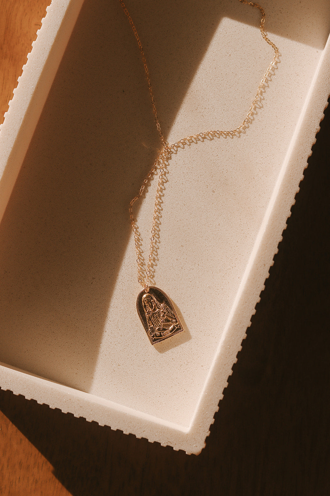 Gold-tone St. Catherine pendant necklace with arch charm displayed on chain.
