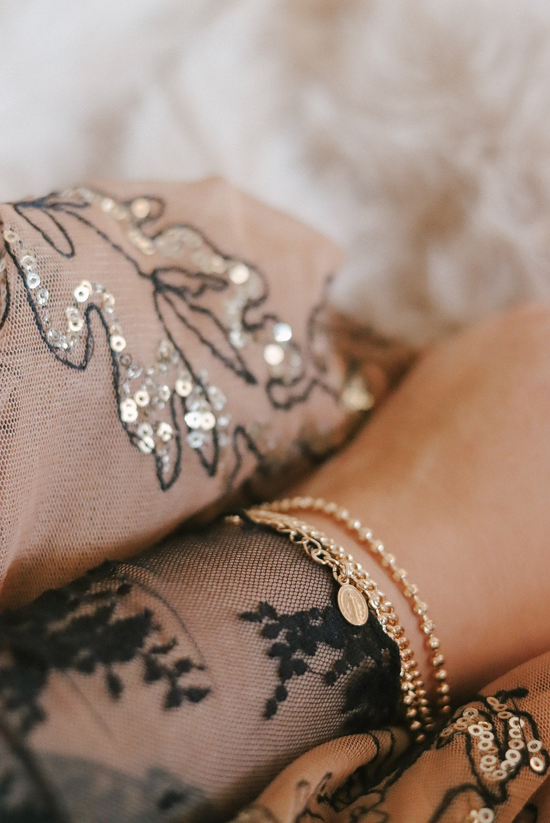 Gold-tone chain bracelet with small oval medal charm, layered on wrist