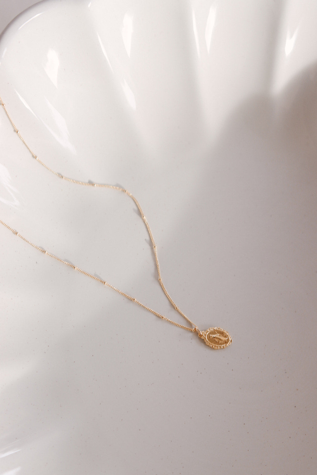 Gold-tone necklace with oval Miraculous medal pendant near chain end