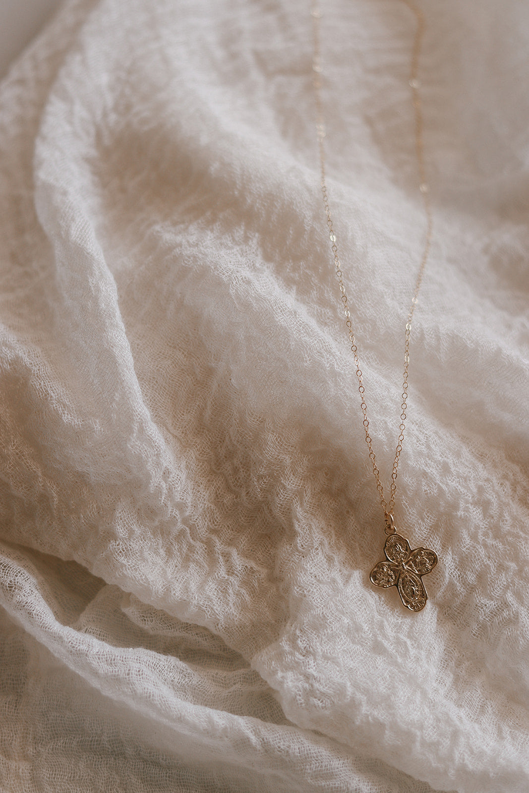 Gold-tone cross pendant necklace with delicate chain, small pendant hanging.