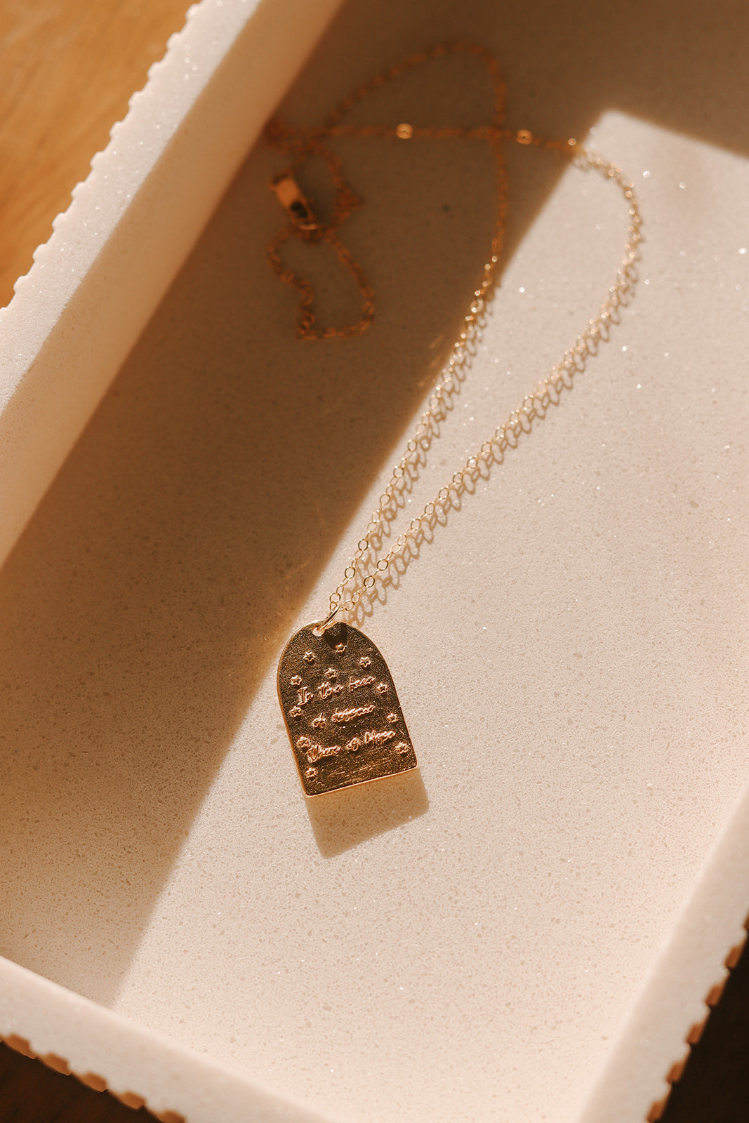 Gold-tone pendant necklace with rectangular plaque charm and engraved details