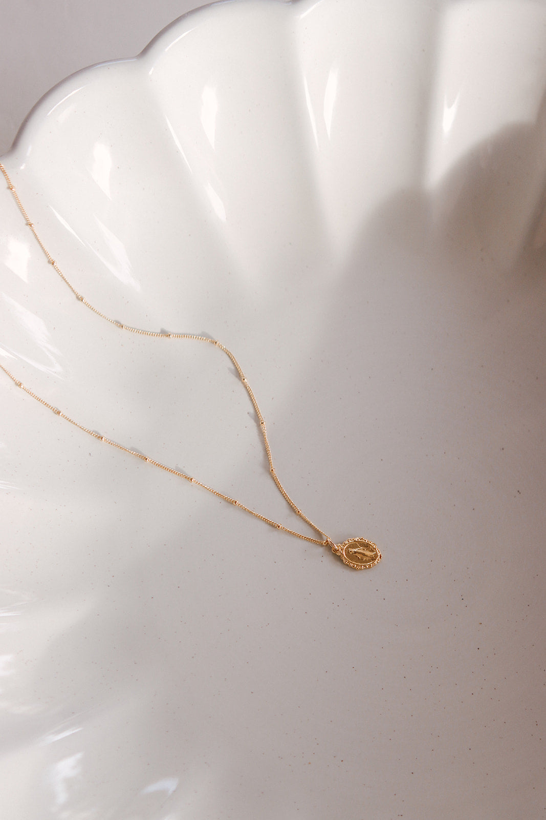 Gold-tone layered necklace with small oval medal charm on fine chains