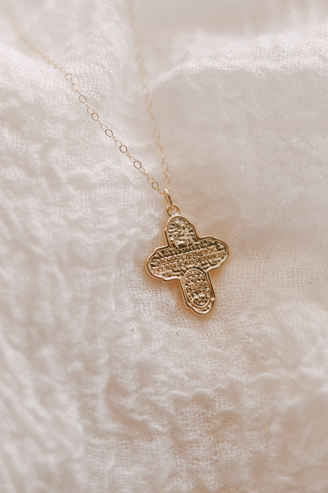 Gold cross necklace with large textured cross pendant on a thin chain