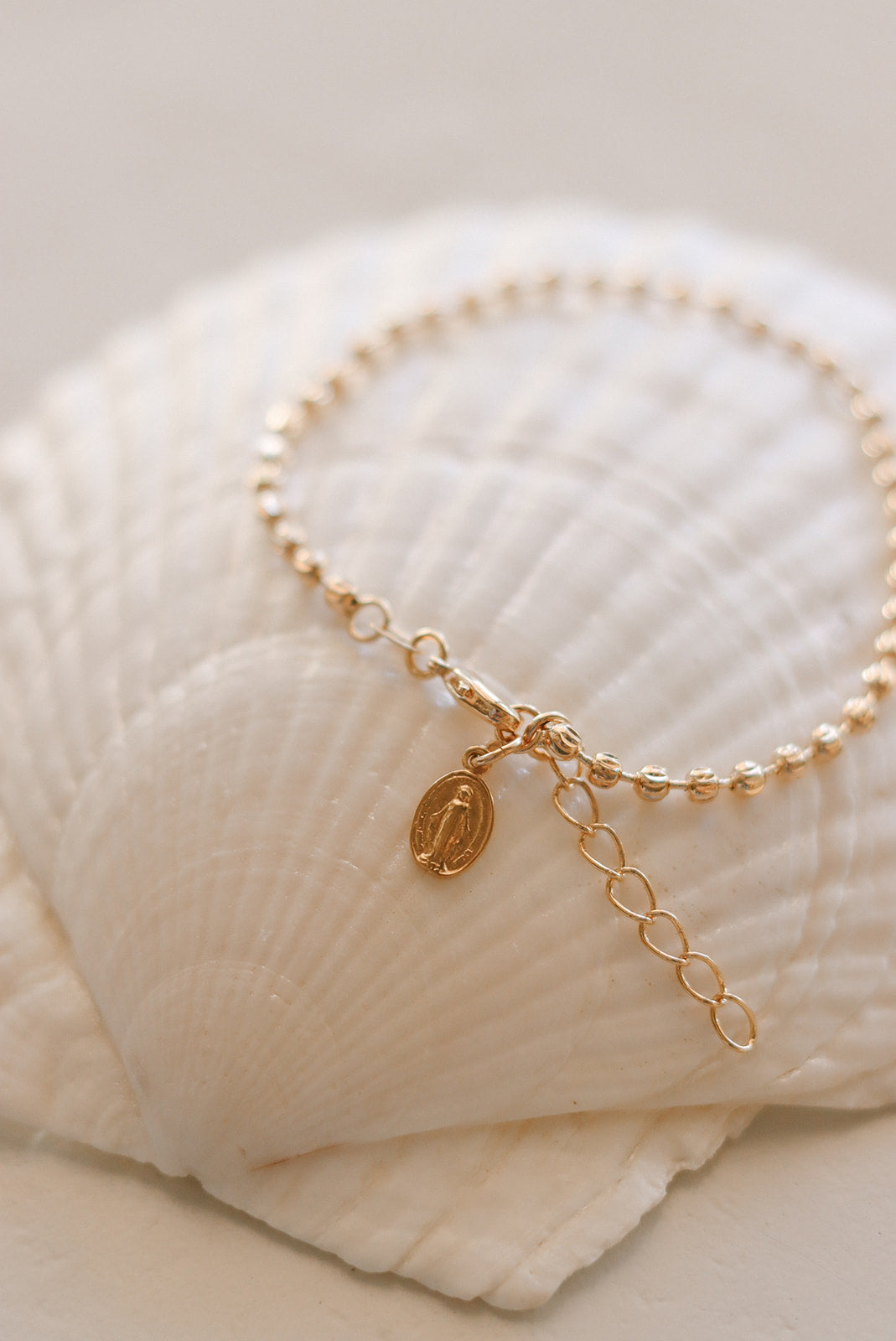 Gold-tone medal charm bracelet with beaded chain and oval pendant charm
