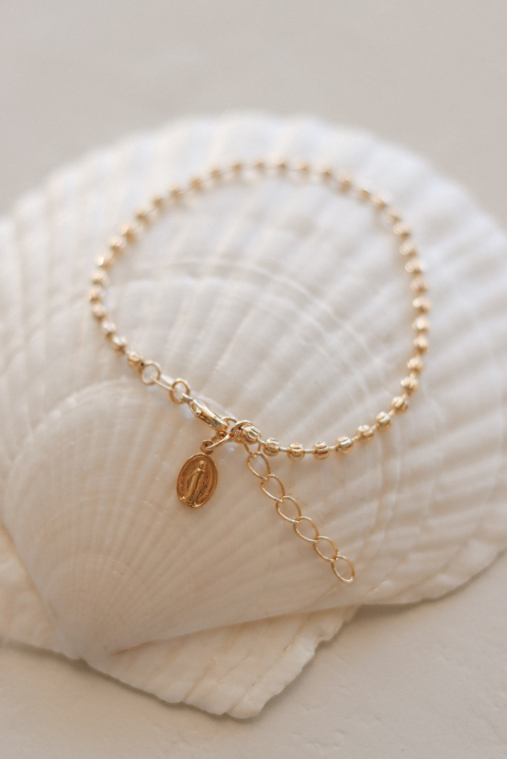 Gold-tone bracelet with pearl-bead strand, link chain, and oval medal pendant