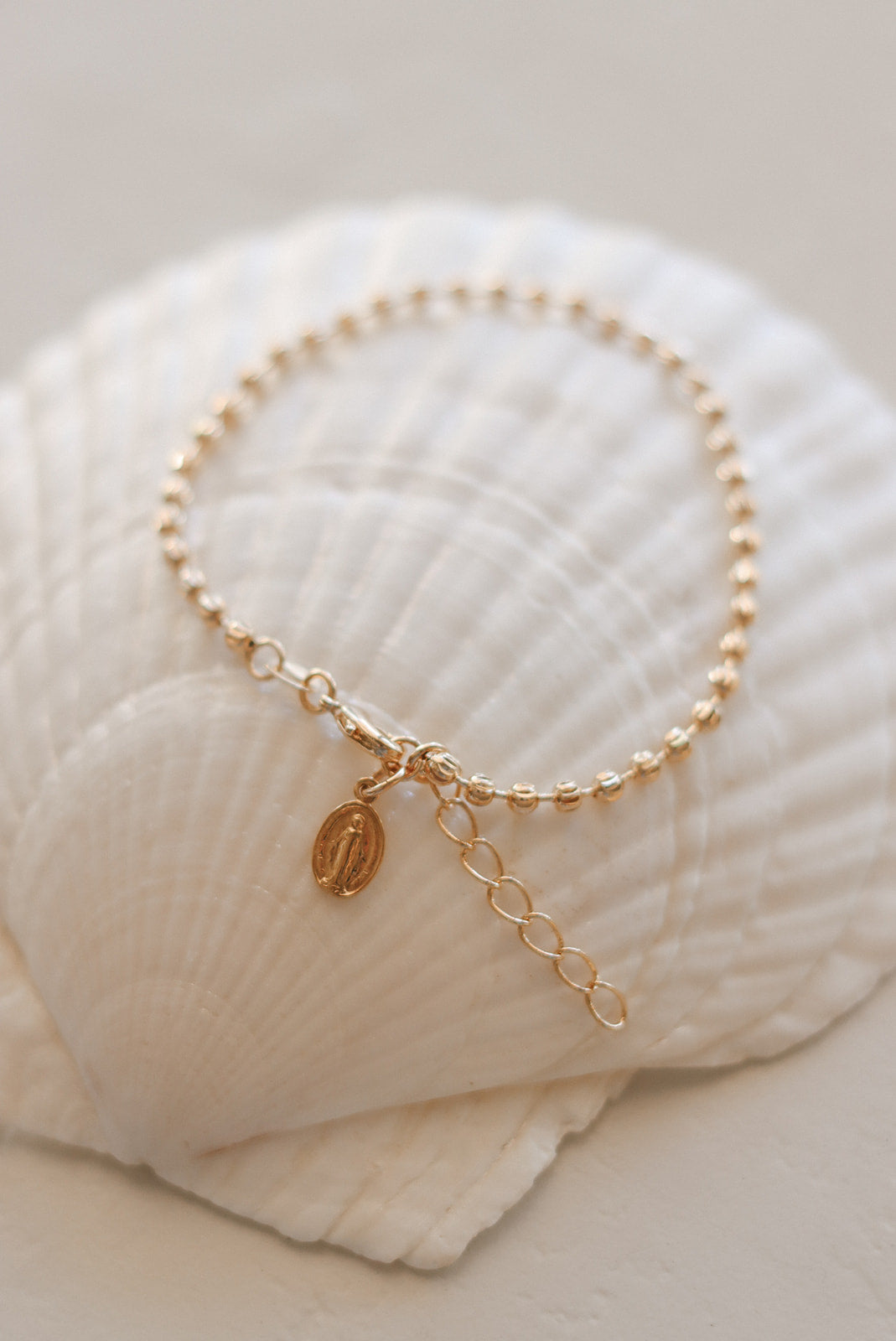 Gold-tone bracelet with pearl-bead strand, link chain, and oval medal pendant