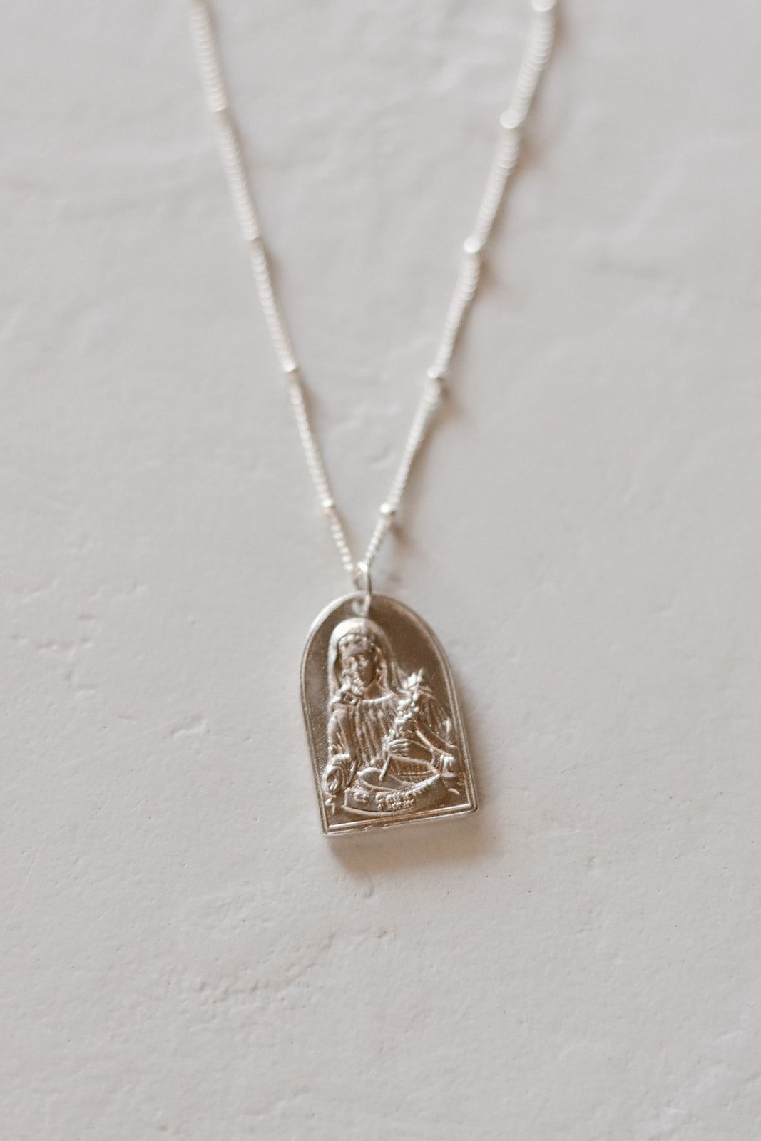 Sterling silver Saint pendant necklace with oval frame and seated figure