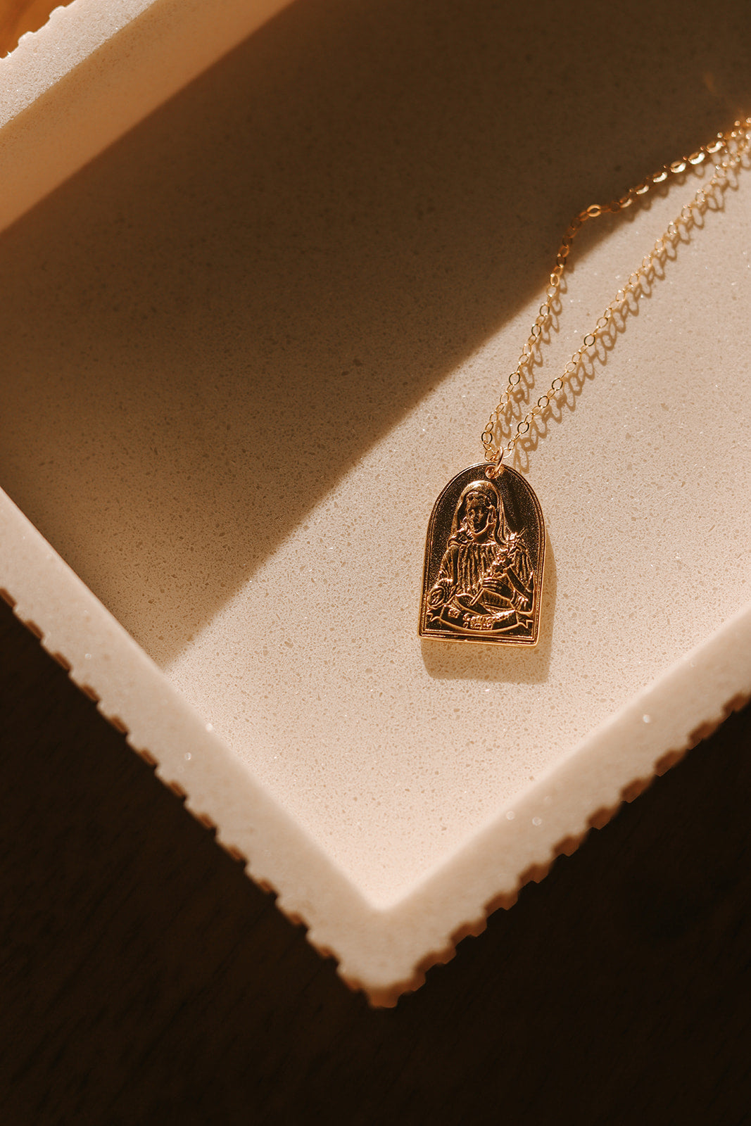 Gold-tone St. Catherine pendant necklace with arched portrait charm on chain.