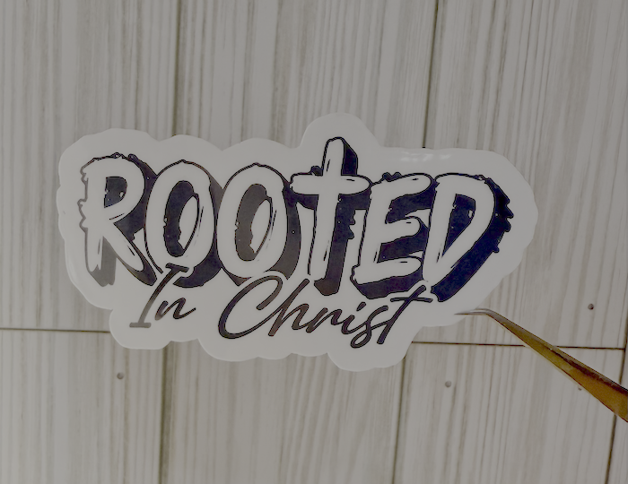 Rooted in Christ vinyl sticker, white background with bold dark text and cross