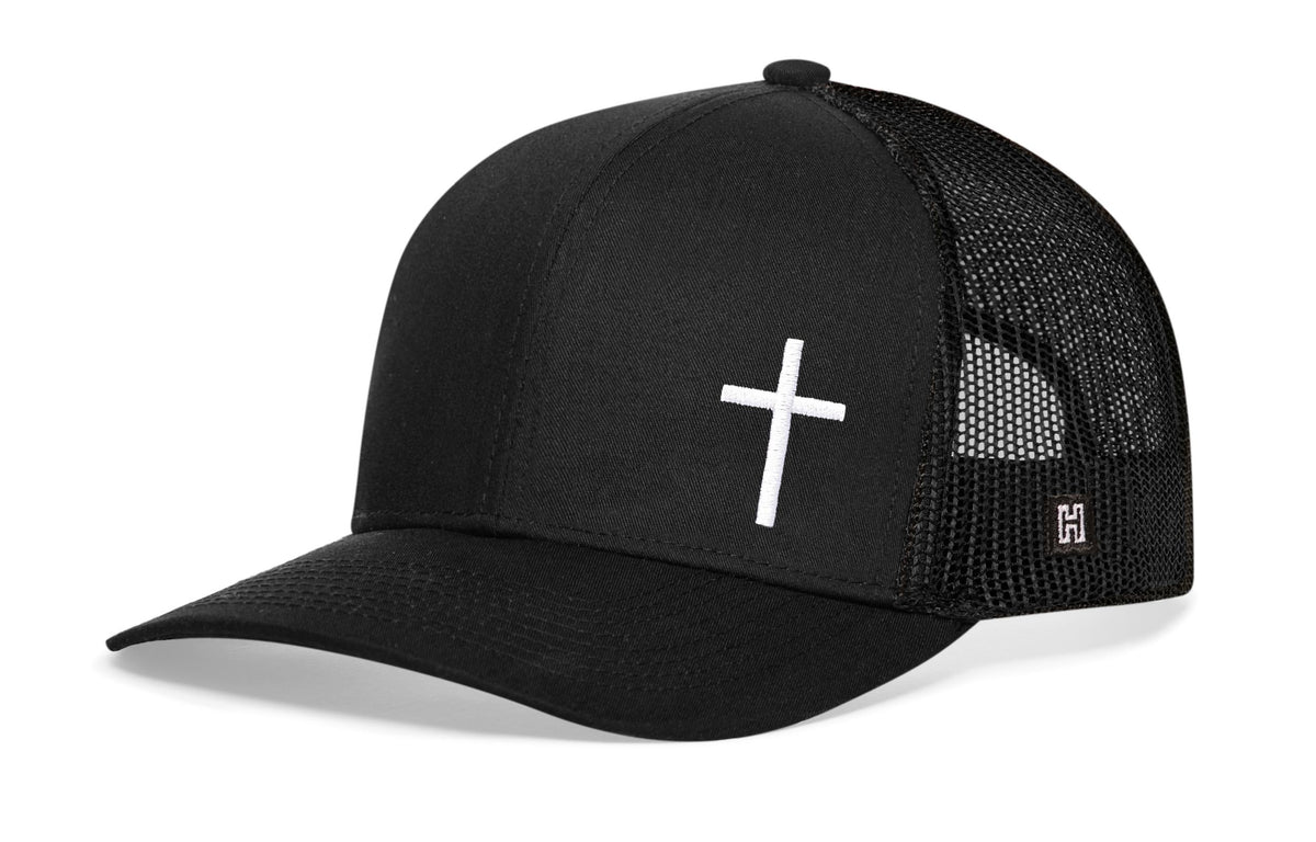 Black trucker snapback cap with white cross on front, mesh sides, snapback.