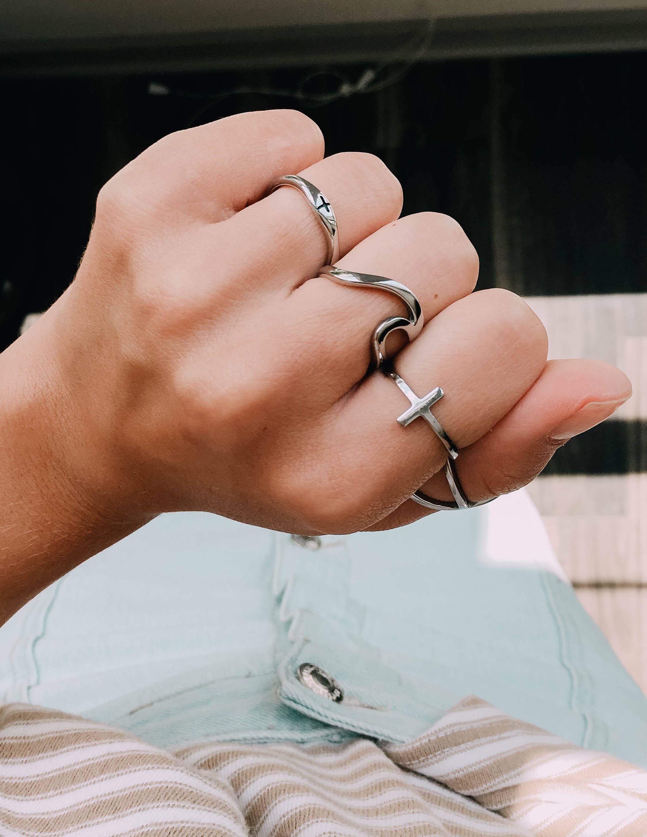 Silver cross ring with thin band and cross motif on hand