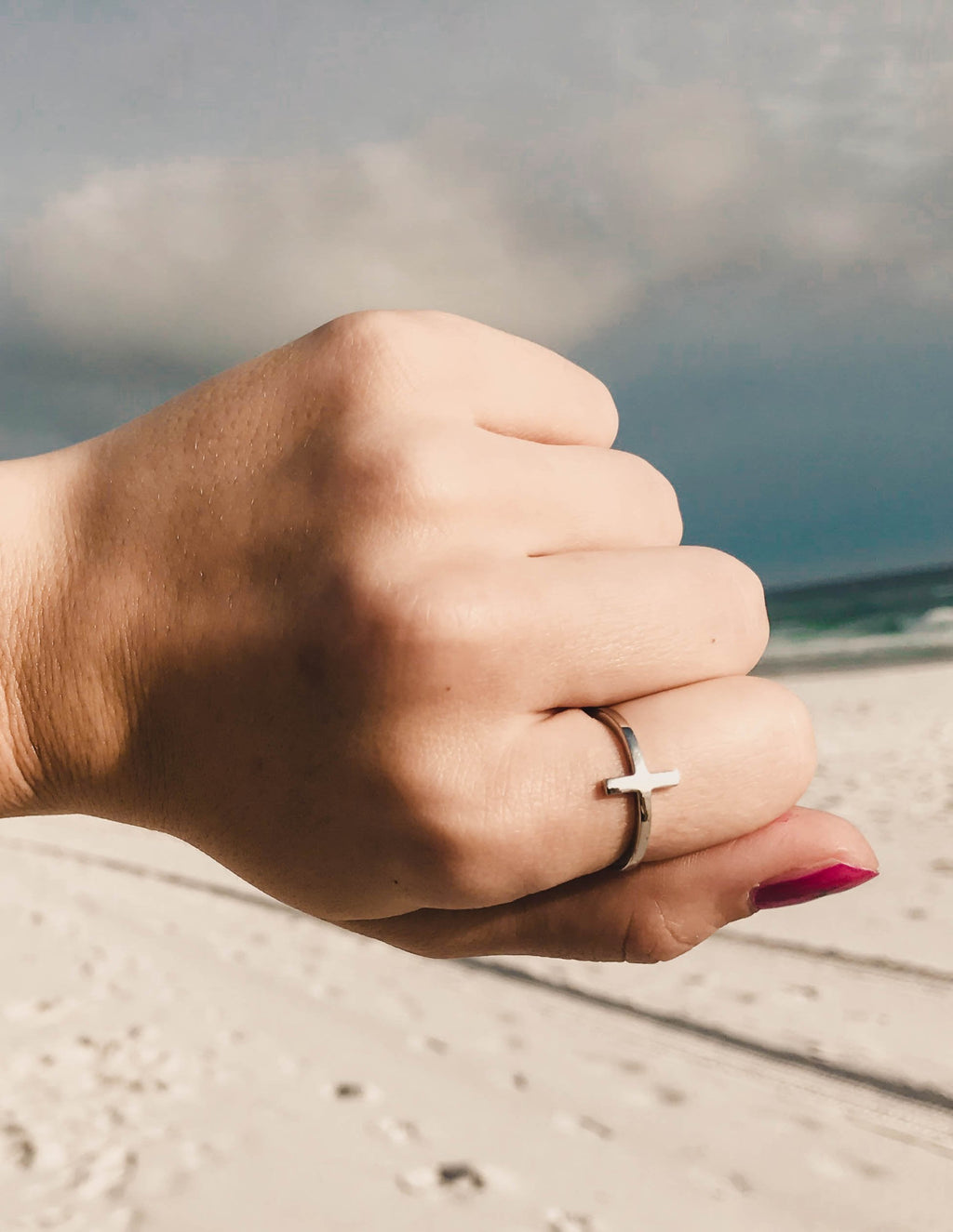 Silver cross ring with cross motif on finger