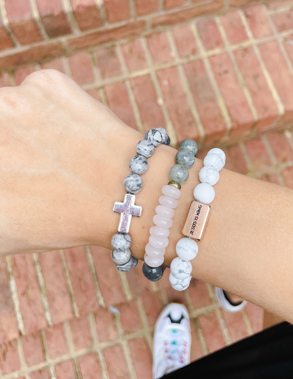 Slate grey beaded bracelet with silver cross charm on wrist