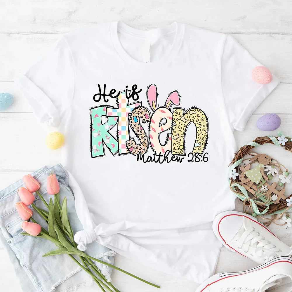 White T-shirt with colorful Easter 'He is Risen' bunny graphic and 'Matthew 28:6'.