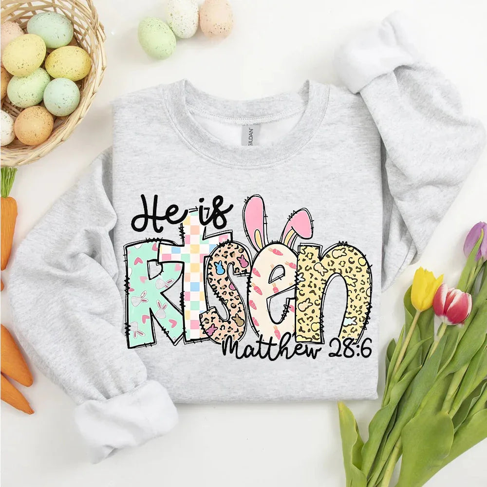 Heather gray long-sleeve T-shirt with colorful 'He is Risen' bunny graphic and 'Matthew 28:6'