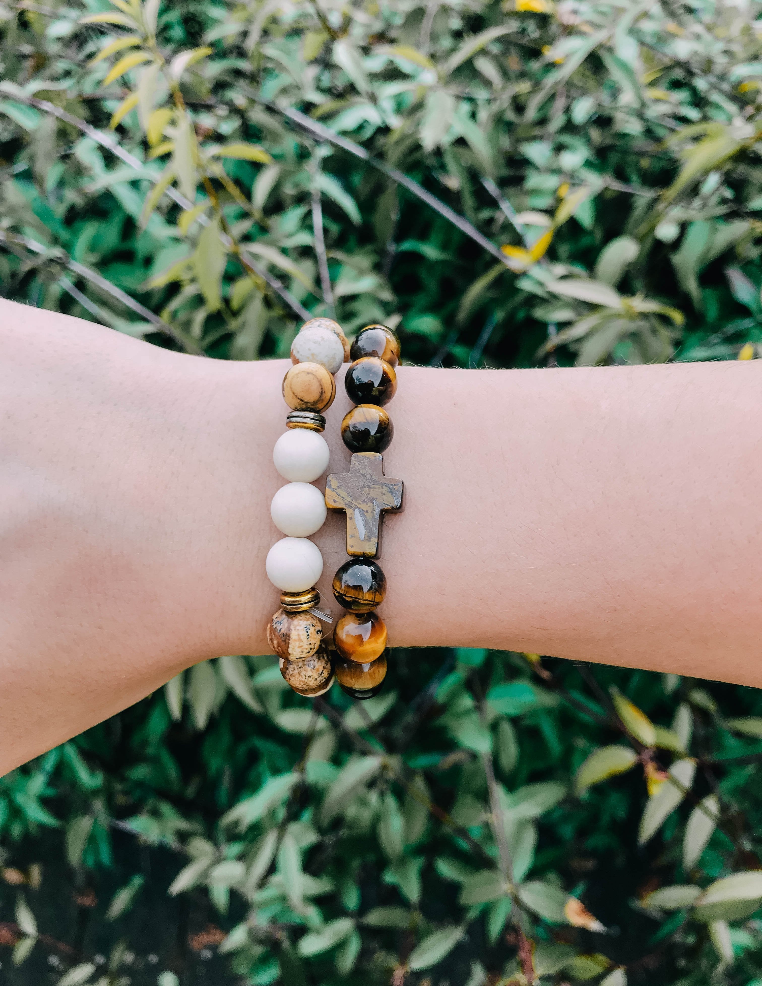 Beaded cross bracelet set on wrist with white and tiger eye beads and metal cross charms