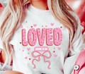White graphic T-shirt with pink 'LOVED' hearts and bow, includes 'JOHN 3:16' text