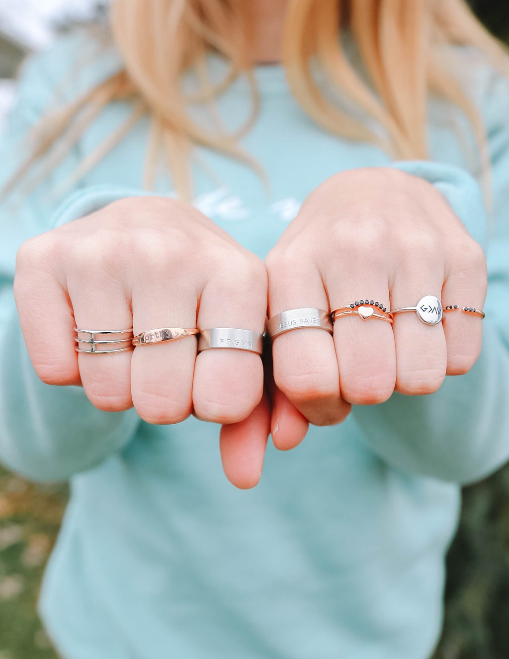 Set of rose gold rings on fingers with thin engraved bands and tiny charm