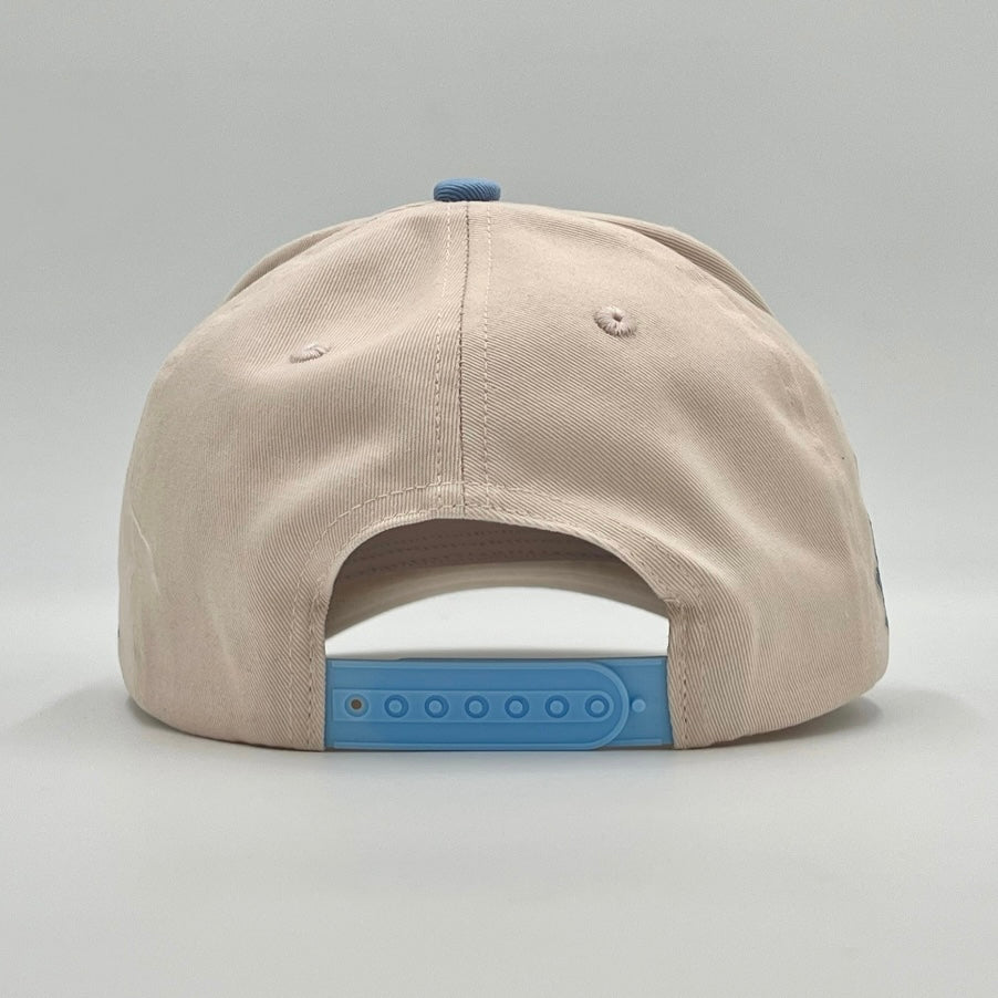 Cream snapback cap back view with vent eyelets and blue snap closure