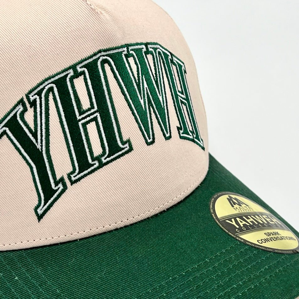 Cream snapback cap close-up with green brim, YHWH front logo, and side badge