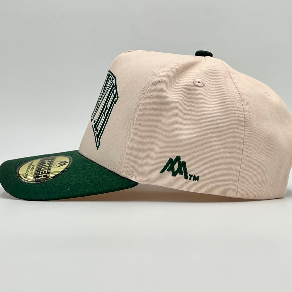 Cream snapback cap with green brim, M logo side text, and circular patch